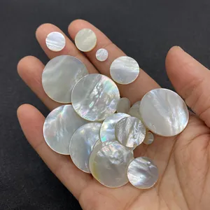 Macro shot of natural white mother of pearl round flat shell pieces held in hand