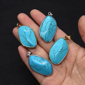 Detailopname van vier turquoise hangers in bladvorm met goud- en verzilverde randen