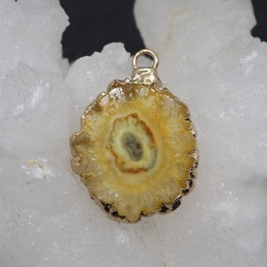Macro view of raw natural crystal stone pendant with golden plated edge and metallic loop