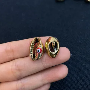 Detailed macro view of gold plated seashell charms featuring a colorful evil eye design