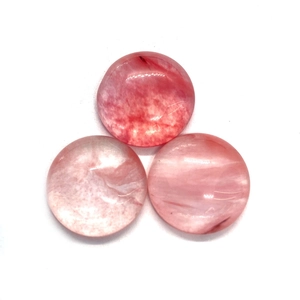 Detailed macro view of three pink round cabochon natural stones with internal texture