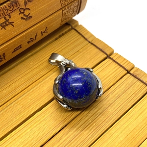 Detailed close-up of blue lapis lazuli ball pendant with silver claw setting on bamboo