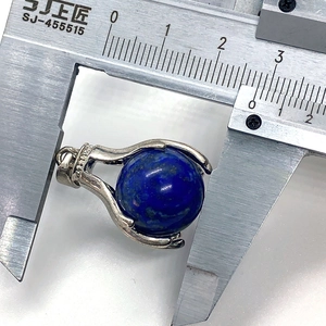 Macro shot of a 25mm lapis lazuli round stone pendant being measured with a caliper