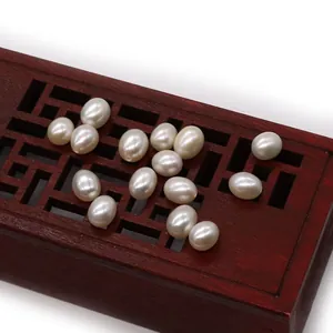 Polished rice-shaped natural freshwater pearls displayed on an ornate red wooden box