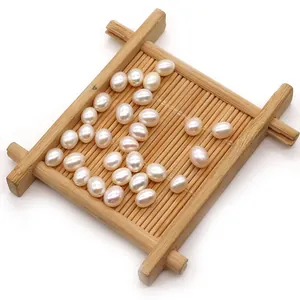 Natural white freshwater rice pearls loosely arranged on a bamboo tray for DIY jewelry