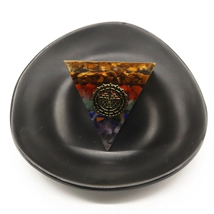 Orgone energy pyramid with natural gemstones and gold geometry on a black tray