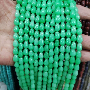 Hand holding multiple strands of light green teardrop shaped watermelon crystal beads