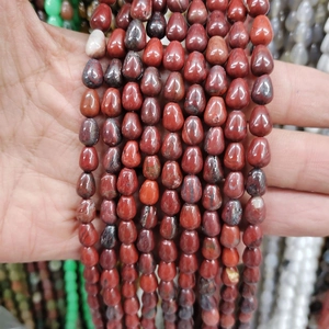Detailed close-up of red teardrop natural stone beads held in hand for size visualization