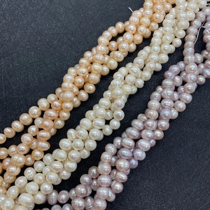 Macro detail of natural freshwater pearls in pink, white and lavender hues on black fabric