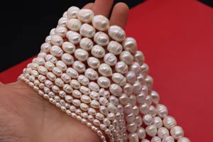 Primer plano de varios hilos de perlas blancas barrocas de agua dulce sostenidas a mano
