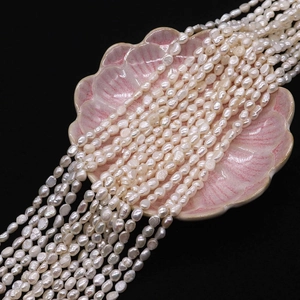 Macro shot of natural freshwater rice pearls on a pink shell dish with black background