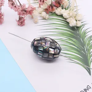 Oval mosaic shell bead with iridescent abalone shell inlay on blue floral background