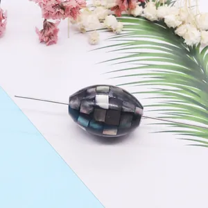 Detailed view of oval mosaic pearl shell bead with iridescent shell inlay for DIY jewelry