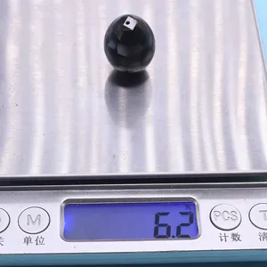 Macro detail of a dark shell bead showing natural texture and 6.2g weight on scale