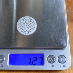 Détail d'un pendentif en nacre de 25mm montrant un poids de 1,27g sur une balance