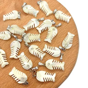 Detail of fishbone-shaped seashell pendants with sparkling cubic zirconia on wood