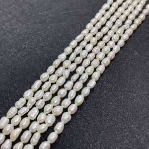 Detailed macro view of 5-6mm natural freshwater rice pearls on a textured black display board