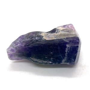 Vue rapprochée d'une pierre d'améthyste naturelle irrégulière violet foncé sur fond blanc