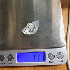 Weight measurement of a natural fan-shaped seashell pendant on a digital scale
