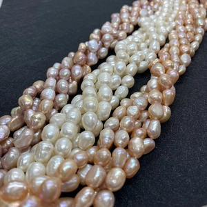 Close-up of white, pink, and lavender freshwater baroque pearls on a black surface