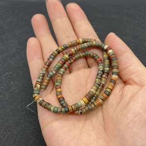 Vista macro de cuentas cilíndricas de ojo de tigre multicolor en la mano para joyería DIY