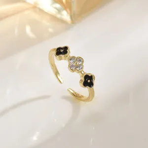 Elegant gold clover ring with black enamel petals and shimmering pave crystals
