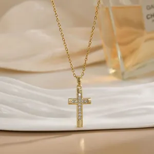 Détail du pendentif croix plaqué or serti de zircons sur un plateau décoratif blanc