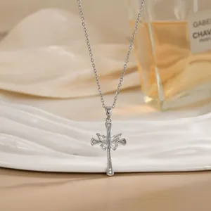 Gros plan d'un collier croix argentée avec pendentif papillon en cristal sur tissu satiné