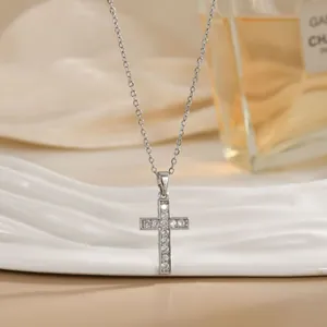Gros plan du pendentif croix argentée avec pierres claires sur chaîne élégante