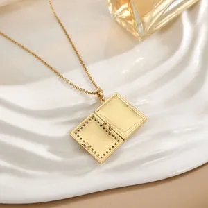Golden book locket necklace with colorful stones on white textured tray display