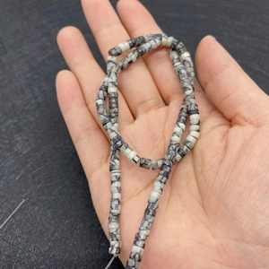 Detalle de cuentas cilíndricas de piedra natural en la mano para joyería artesanal