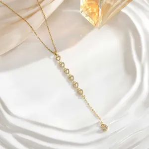 Macro detail of gold Y-shaped necklace with zircon heart charms and silk background