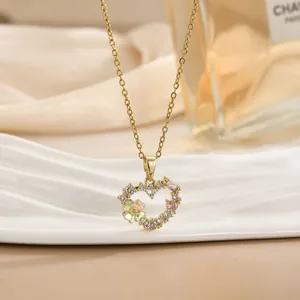 Detail van een gouden hart hanger met roze edelsteen en zirkoon op champagne zijde