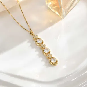 Detail of gold tassel necklace featuring three round zircons and four-petal floral accents