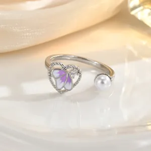 Macro shot of silver open ring featuring a purple enamel butterfly and a white pearl