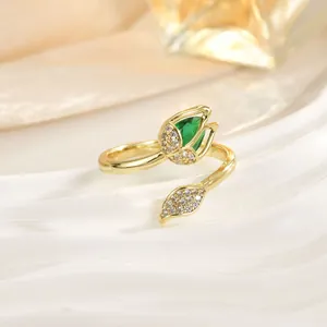 Macro detail of tulip ring featuring a green teardrop stone and zircon-encrusted gold petals