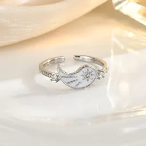 Detailed close-up of adjustable silver ring with white enamel inlay and sunburst stone