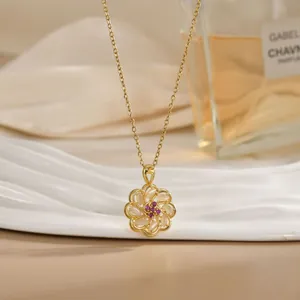 Detailed close-up of a golden flower pendant necklace with opal petals and red crystals