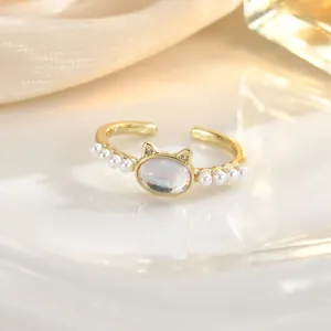 Detail of a cat-shaped ring with iridescent oval stone and white faux pearls on silk