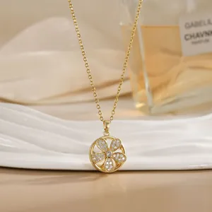Detailed close-up of a rotating gold flower pendant necklace with sparkling crystal inlay