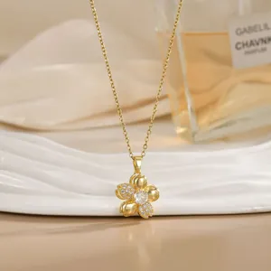 Close-up of a rotating gold flower pendant necklace with crystals on white tray