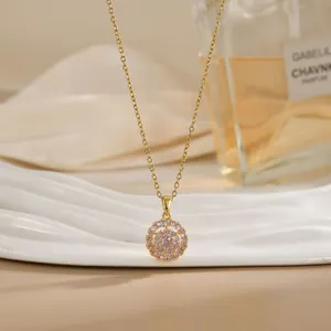 Close-up of golden necklace featuring a spinning flower pendant with pink zircons