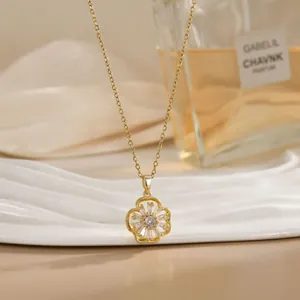 Close-up of rotatable golden flower pendant with clear zircons on a wavy white tray