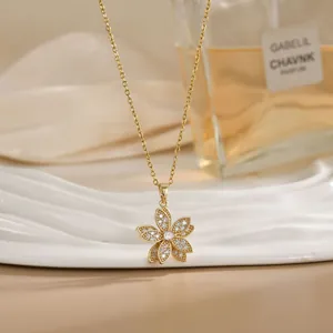 Close-up of rotatable 18K gold flower necklace with zircon inlay on a white ceramic plate