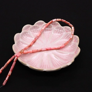Vista macro di perle cilindriche in conchiglia rosa 4x8mm con lucentezza naturale