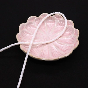 Dettaglio di perle cilindriche in madreperla bianca 4x8mm su un vassoio decorativo