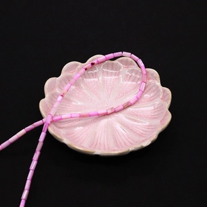 Dettaglio macro di perle cilindriche in conchiglia naturale rosa 4x8mm in vassoio di ceramica