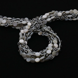 Makro-Detail von natürlichen Muschel-Evil-Eye-Perlen mit lila und gelbem Öl-Finish