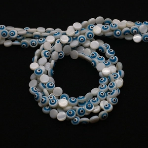 Makroaufnahme flacher Muschelperlen mit blauem Evil Eye Muster für Schmuckherstellung