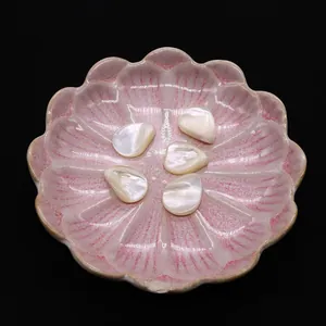 Makroaufnahme von 5 Naturperlmutt-Tropfenperlen auf einem rosa Blütenkeramikteller